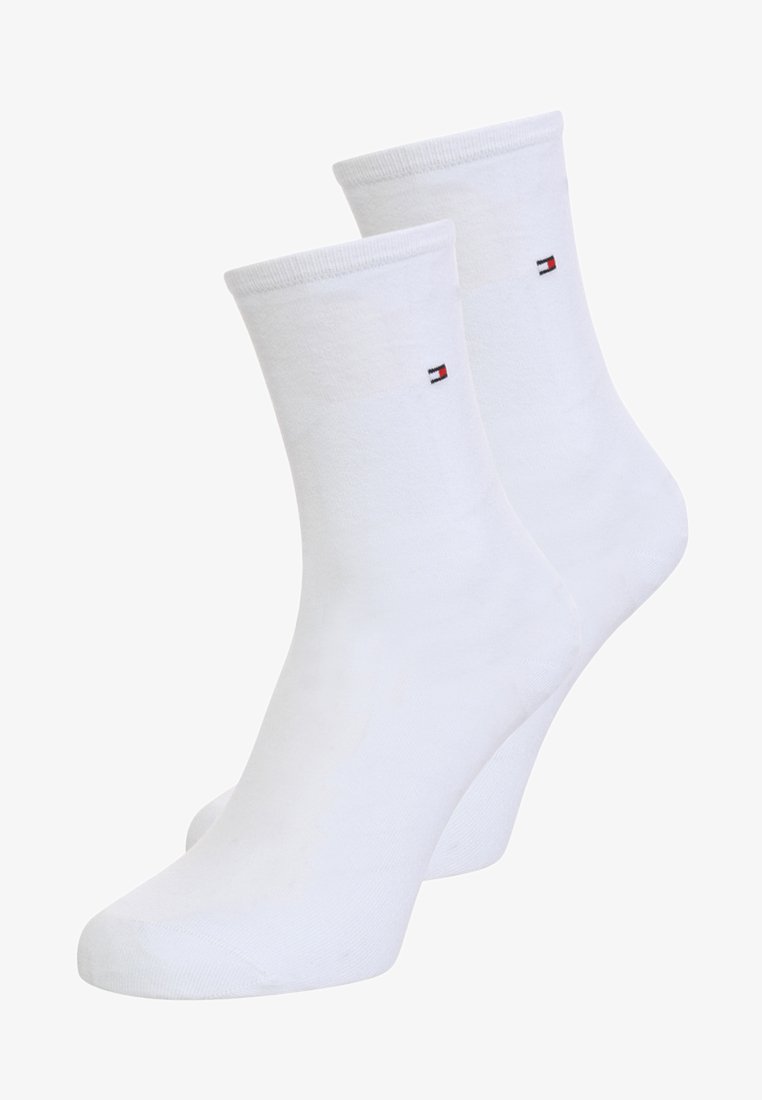 White cotton ankle socks with a ribbed cuff, featuring a small logo patch in red, white, and blue on the outer side.