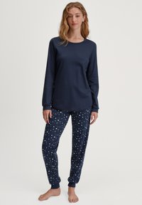 Marineblauwe lange mouwen top gecombineerd met marineblauwe pyjamabroek met een patroon van een halve maan, gemaakt van zachte, lichte stof.