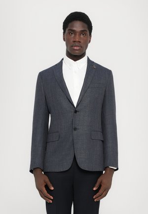 Marineblau strukturierter Blazer mit Revers, zwei vorderen Taschen und einem Knopfverschluss, getragen über einem weißen Hemd.