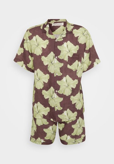 Lina divdaļīga apģērba komplekts, kas sastāv no īsām piedurknēm krekla un atbilstošām šortiem, uz brūna fona ar lieliem zaļiem hibiska ziedu rakstiem.