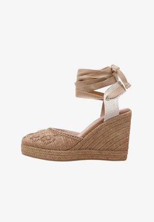 Espadrille à talon compensé beige avec texture tissée et détails floraux brodés sur le bout. Dispose d'une longue sangle de cheville en tissu et d'une semelle plateforme en jute.