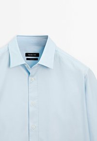 Camicia azzurro chiaro con colletto classico, caratterizzata da una patta frontale con bottoni bianchi. Realizzata in tessuto morbido, con una texture liscia.