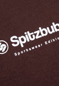 Brauner Baumwollstoff mit weißem Text, der "Spitzbub" und "Sportswear Edition" liest, sowie einem kreisförmigen Logo-Design auf der linken Seite.