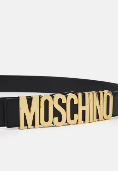 Must mustrihihvööriga must nahkvyö, millel on silmatorkav kuldne logo, mis kujutab sõna "MOSCHINO" pandlana. Sujuv tekstuur ja stiilne disain.