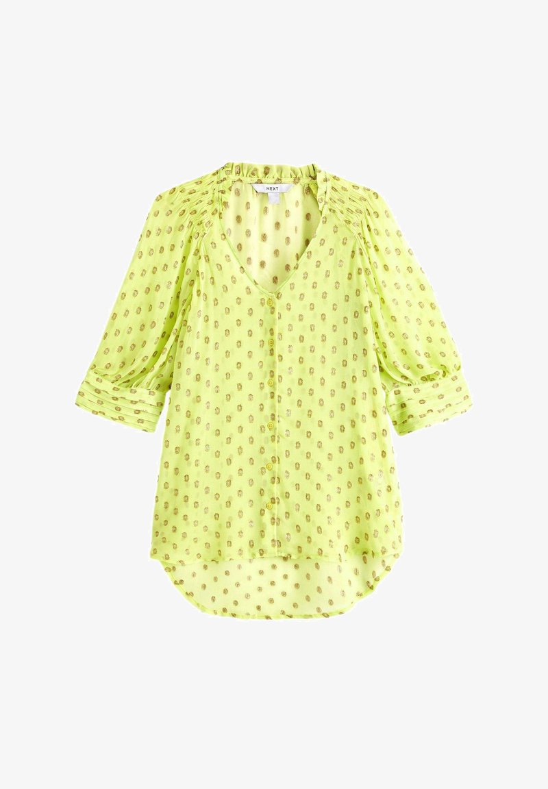 Blouse vert clair à pois dorés, col en V, boutons devant, manches 3/4 et coupe décontractée et ample.