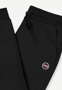 Mustad mustad, mis on valmistatud pehmest kangast, ribataänava, reguleeritava paelaga, küljetaskutega ja ümmarguse 'Colmar' logopatchiga.