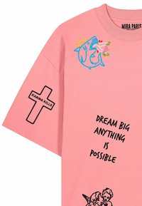 T-shirt rose avec broderie d'un requin mordant une fleur, croix noire avec "Karma Kills" sur la manche, texte "Dream Big Anything Is Possible" et impression de chérubins.