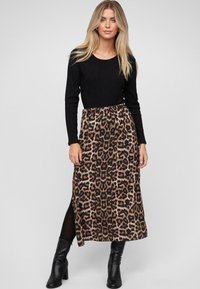 Czarny prążkowany top z długim rękawem, zestawiony ze spódnicą w brązowy leopardski wzór o średniej długości, z bocznym rozcięciem i czarnymi kozakami do kolan.