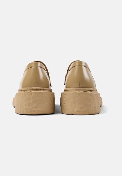 Tanschoenen met een afgerond ontwerp, voorzien van een dikke, gestructureerde beige zool. Gladde bovenkant met gestikte details bij de naden.