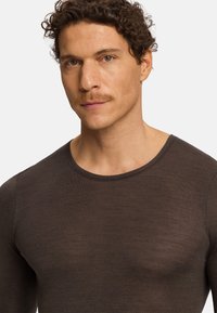 Camisa marrón de manga larga hecha de una tela ligera, con un cuello redondeado y un diseño ajustado, con una textura suave.