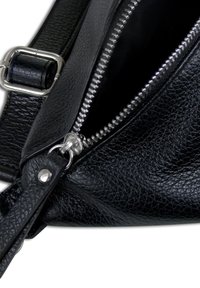 Zwarte leren handtas met een gestructureerde afwerking, voorzien van een zilveren rits en hardwareaccenten. De schouderband heeft een gespdetail.