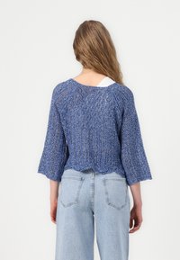 Pull en tricot bleu avec une coupe ample, des manches trois-quarts et un ourlet à volants. La texture est aérée et légère, mettant en valeur un design décontracté.