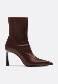 Stivale alla caviglia in satin marrone con punta affusolata, silhouette aderente e tacco lucido. Presenta cuciture senza soluzione di continuità e un design elegante.
