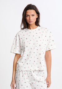 Camiseta blanca de manga corta con un patrón repetido de cerezas rojas y verdes y hojas. Fabricada en suave algodón con un corte relajado.