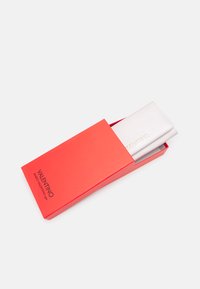 Silver wallet with a textured finish displayed partially in a bright red box, featuring the brand name in black on the front.