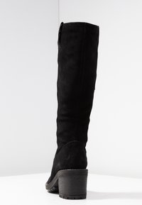 Botte noire en daim montant jusqu'au genou avec un talon bloc, présentant une texture lisse et des détails de couture subtils à l'arrière.