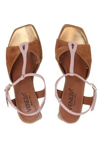 Brune ruskind sandals med blokhæle, en metallisk guld tåcap, lyserøde ankelremme og teksturerede detaljer på hælen.