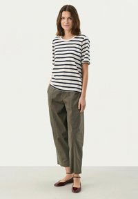 Striped cotton T-shirt with short sleeves in navy and white, paired with olive green tapered trousers and burgundy flats.