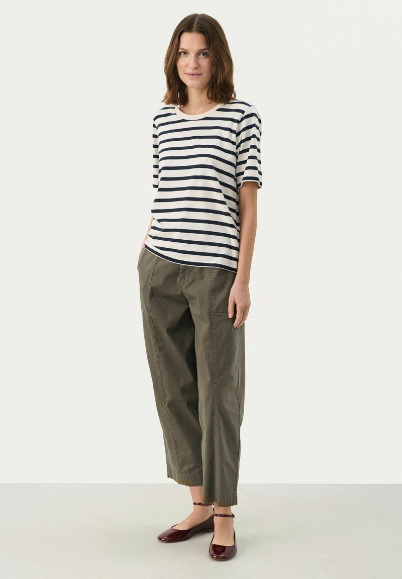 Striped cotton T-shirt with short sleeves in navy and white, paired with olive green tapered trousers and burgundy flats.
