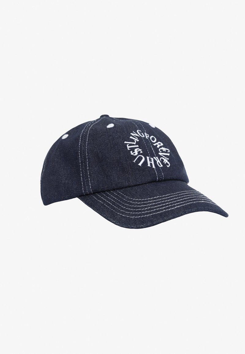 Denim baseball cap i mørkeblå med hvid syning og øjler. Har cirkulær, hvid broderet tekst på fronten.