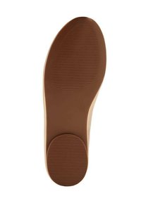 Suola di una scarpa in gomma marrone, con una superficie liscia caratterizzata da motivi ovali concentrici e un'area di presa texture vicino al tallone.