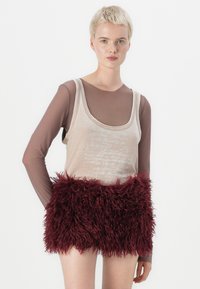 Beige ujjatlan top felirattal, egy barna áttetsző hosszú ujjú ing fölé rétegezve. Burgundi puha szoknya, texturált anyaggal a derékrészen.