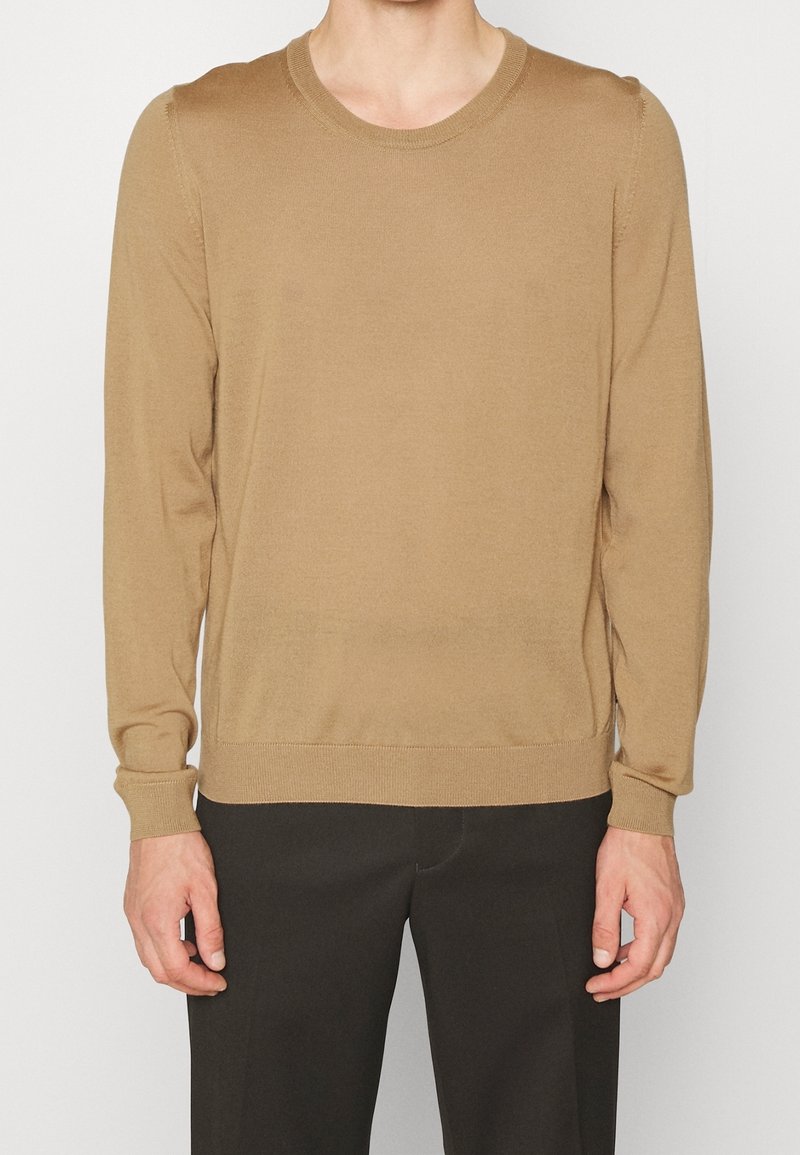 Pull à manches longues marron clair en tissu tricoté doux. Il présente un col rond ainsi que des poignets et un ourlet côtelés, offrant une silhouette ajustée.