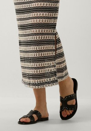 Zwarte leren slidesandalen met kruislingse bandjes, versierd met zilveren studs. Het ontwerp heeft een vlakke zool en gedetailleerde stiksels.