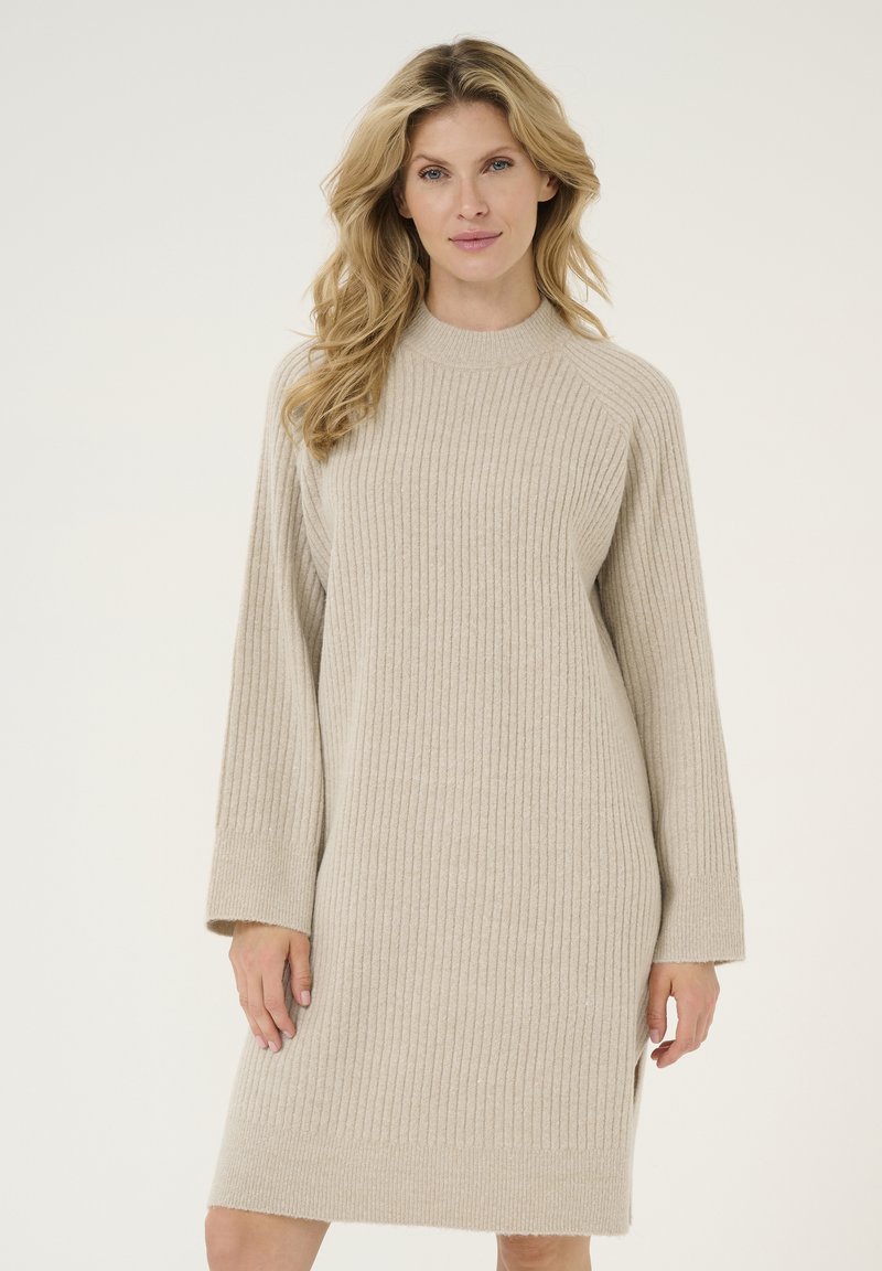 Robe pull en tricot côtelé beige avec un col montant et des manches longues, dotée d'échancrures sur les côtés à l'ourlet pour plus de confort et de style.