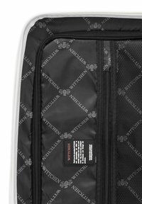 Black travel bag interior with a repeating logo pattern, featuring mesh pockets and a fabric care label. Smooth texture with zippered compartments.