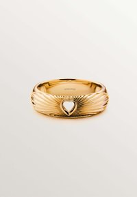 Anillo de oro con intrincados grabados en forma de alas, que presenta un corte en forma de corazón hueco en el centro. Acabado suave y pulido.