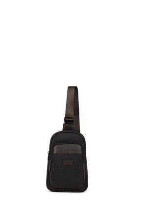 Sac bandoulière compact noir et marron foncé avec une poche zippée à l'avant et une bandoulière réglable sur fond blanc.