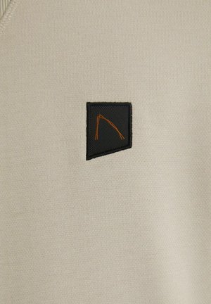Lichtbeige trui van zachte stof, met een zwarte patch met een oranje geometrisch ontwerp. Glad textuur en eenvoudig, modern ontwerp.