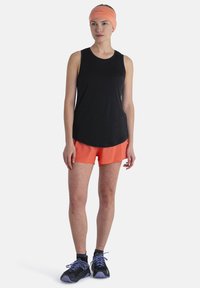 Top negro sin mangas, pantalones cortos naranjas, calzado negro con acentos morados. Tela suave, ajuste relajado, diseño simple, adecuado para ropa deportiva.