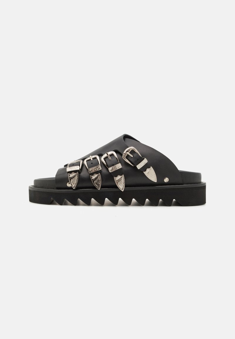 Sandales noires à glissière avec plusieurs fermetures à boucle en argent, une semelle épaisse à crans et une texture lisse. Design simple avec un motif ouvert à l'avant.