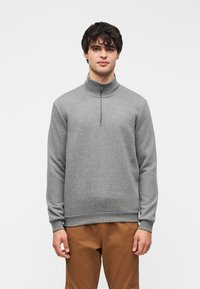 Γκρι φλις πουλόβερ sweatshirt με όρθιο γιακά, εμπρόσθιο φερμουάρ μέχρι τη μέση, ριμπ μανσέτες και τελείωμα. Το υλικό έχει απαλή, λεία υφή.