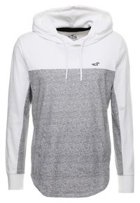 Grå och vit huvtröja med ett helt vitt övre parti, en melerad grå underdel och en liten logotyp på bröstet.
