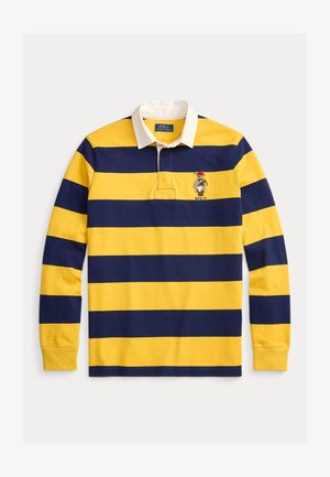 Sárga és tengerészkék csíkos, hosszú ujjú rögbiing fehér gallérral és a mellkason hímzett logóval. Pamut anyagból készült.