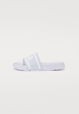 Sandale à talon plat en caoutchouc souple de couleur violette. Elle présente une large sangle avec des rayures blanches horizontales et un logo, une semelle plate et une texture lisse.