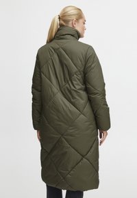 Olivengrønn, knelengd pufferjakke med høg krage og diamantmønstret quilting. Har lange ermer og en avslappet passform.