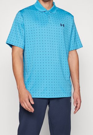 Man wearing light blue polo shirt with small dark cross patterns and dark logo, paired with dark blue pants.
