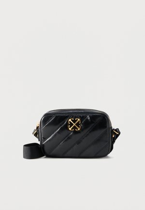 Geantă crossbody din piele neagră matlasată, cu emblemă logo aurie și curea reglabilă din material textil negru, pe fundal alb.