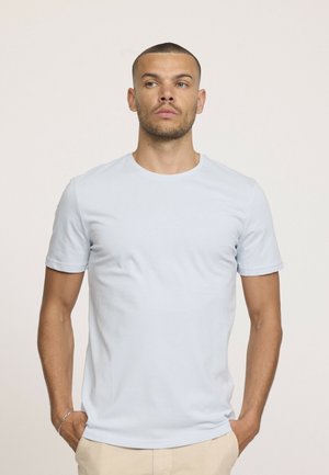 T-shirt bleu clair à manches courtes et col rond, fabriqué en tissu doux, présentant un design ajusté et une texture lisse, exposé sur un fond neutre.