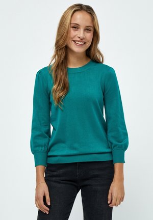 Teal pullover neulepusero, jossa on ribbitty kaula-aukko ja hihansuut, kolmannes-mittaiset hihat ja pehmeä tekstuuri. Yhdistetty tummiin farkkuihin.