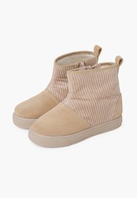 Botas de tobillo beige con parte superior de textil acanalado, punta y talón de ante, acentos laterales elásticos y suela de goma para tracción.
