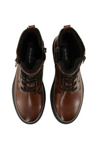 Bottes chevilles en cuir marron avec lacets noirs, fermeture éclair et intérieur doublé de fourrure douce. Semelle en caoutchouc plate avec des détails texturés.