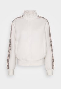 Chaqueta blanca con cremallera, hecha de tela suave, con cuello alto, bolsillos laterales y ribete con estampado a lo largo de las mangas.