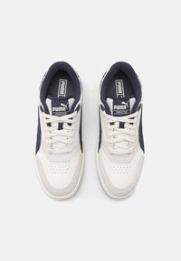 Sneakers atletiche bianche e blu navy con finitura in pelle liscia e suede, dotati di punta perforata, design con lacci arrotondati e accenti del logo.