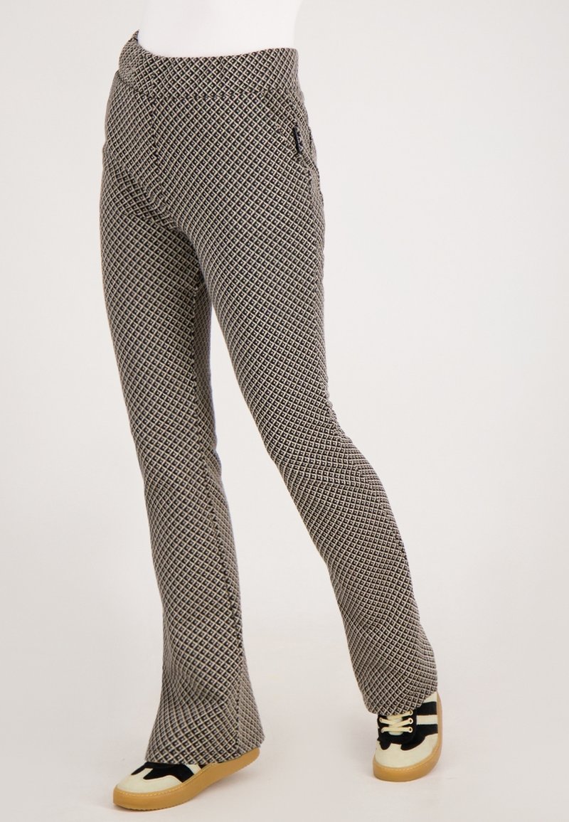 Geprinte flared broek in zwart en beige, met een geometrisch ontwerp, een gladde textuur en zijzakken. Gecombineerd met zwarte sneakers.