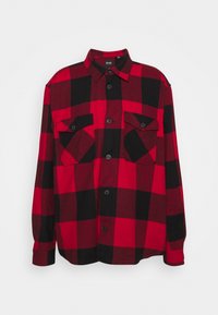 Camicia di flanella a quadri rossi e neri con chiusura a bottoni, due taschini sul petto e maniche lunghe con polsini a bottone.